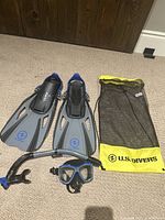 Full set including fins, snorkel mask, snorkel tube, and storage bag on carpeted floor.