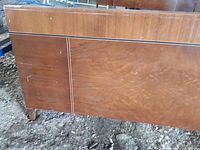 Close-up image of the wooden footboard showing the grain, panel design, and metal trim detail.