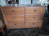 Front view of wooden dresser showing six drawers with decorative round metal handles.