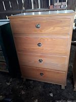 Full front view of wooden high dresser with four drawers showing wood grain and metal drawer pulls