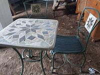 Photo showing the garden table and one chair side by side, highlighting the metal frames and mosaic design on table top and chair back.