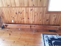 Photo of the long pine shelf placed against a wood-paneled wall, showing wood grain, knots, and shelf length.