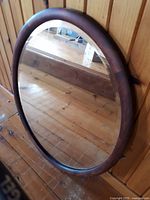 Oval wooden frame vintage mirror with beveled glass, showing reflective surface and rounded frame edges.