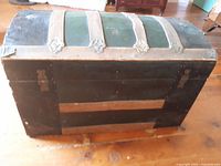 Front and top view of the closed small humpback trunk showing wooden and metal construction with curved top.