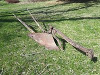 Full view of single-furrow plough showing metal share, beam and wooden handles