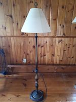 Full view of the vintage floor lamp showing wooden shaft, metal base, and beige fabric lampshade.