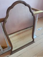 Full view of vintage wooden framed mirror with decorative shaped frame.