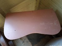 Top view of the pink pine desk showing the scroll shaped top and surface wear.