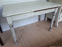 Front view of vintage pine table showing distressed white crinkle paint on legs and worn tabletop