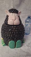 Front view of black sheep cookie jar next to a water bottle for size reference