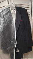 Black tuxedo jacket with red pocket square hanging with garment bag