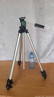 Slik 92S tripod fully extended with water bottle for scale, showing aluminum legs, leg locks, pan/tilt handle, and mounting plate