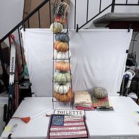 Full view of vertical metal pumpkin stand with 7 pumpkins in fall colors and assorted fabric pieces spread below.