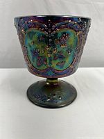 Side view of Fenton Wild Strawberry carnival glass compote showing iridescent colors and embossed berry and leaf pattern.