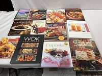 Full lot of 12 cookbooks arranged in a grid, showing titles and cover images including Hawaii Baking, Stir-Fry, Wok, Cookies, Cupcakes, and Christmas recipes.