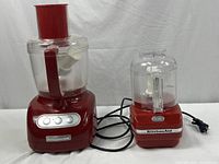Photo of two KitchenAid kitchen appliances: a large food processor and a smaller attachment, displayed together with cords visible.