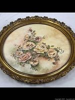 Full front view showing oval domed floral oil painting in ornate gold gilt frame.