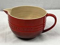 Full side view of Le Creuset batter bowl showing cerise red exterior and handle.