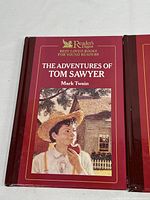 Front cover of The Adventures of Tom Sawyer hardcover book with red binding and illustration of boy eating an apple.