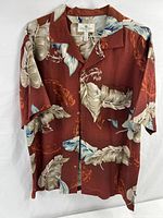 Front view of vintage red Hawaiian shirt with feather pattern on hanger.