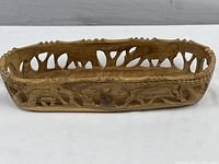 Front view of rectangular wood bowl showing detailed elephant carvings along the side and openwork rim.