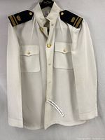 Full front view of vintage US Navy white dress shirt on hanger showing epaulets with rank insignia and gold buttons.