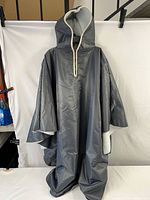 Full view of the poncho hanging showing its water resistant outer fabric and oversized cut.