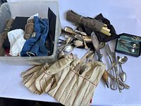 Wide view of plastic tub holding cloth rolls and assorted flatware spilled onto white surface