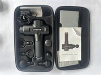 ECOGUN deep muscle massager and accessories in hard carrying case, includes four interchangeable heads, power cord, and instruction booklet.