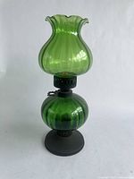 Full view of green fluted glass oil lamp showing entire structure from base to flared chimney.