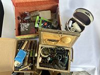 Overview photo showing three containers with mixed sewing supplies including thread spools, cords, leather pieces, measuring tape, and small tools.
