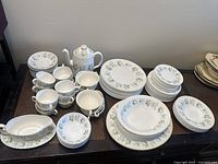 Full spread of Minton Spring Valley china set arranged on table showing dinner plates, salad plates, bowls, cups, saucers, teapot, and gravy boat.