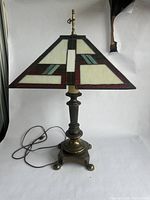 Full view of the Tiffany style stained glass table lamp with brass base and cord laid out.