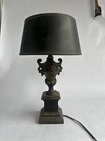 Full view of lamp showing black fabric shade and detailed metal base.