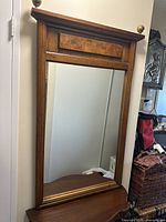 Full view of the rectangular wall mirror showing medium brown wooden frame and reflective glass.