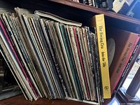 Side view of vinyl record collection showing worn sleeves and collection size