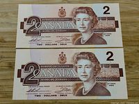 Front view of two 1986 Canadian 2 dollar notes stacked, showing Queen Elizabeth II's portrait and denomination 2