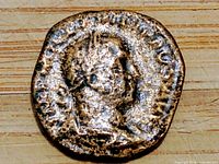 Obverse side of the ancient coin with a male profile and circular inscriptions.