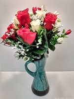 Front view of ceramic vase with artificial flower bouquet arranged inside