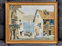 Full view of the framed print depicting a coastal village scene with buildings and boats.