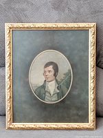 Framed vintage portrait print of a man in green jacket and white cravat, with oval mat and ornate gold-tone wooden frame.