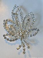 Front view of large leaf-shaped brooch adorned with clear Austrian crystals showing design and size.