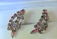 Close-up of pink rhinestone clip-on earrings showing silver-tone metal and pink round and marquise rhinestones.