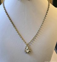 Front-facing photo of a 16 inch rhinestone necklace displayed on a mannequin, showing clear rhinestones and a teardrop pendant.