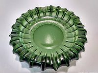 Top-down view of a green glass ashtray with ruffled edges, showing glossy finish and textured center.