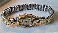 Front side of a vintage ladies wristwatch showing silver-tone rectangular dial and expandable metal bracelet.