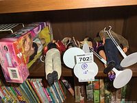 Six dolls shown on a shelf, including the boxed Britney Spears doll and several loose dolls with stands.