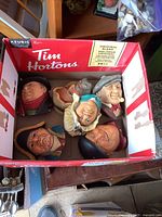 Photo showing all six different Bosson heads in a Tim Hortons cardboard box, viewed from top, showing colorful character heads with some wear.