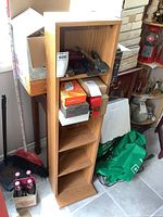 Photo of wooden media storage shelf filled with various boxes and small items, showing the front and side angles.