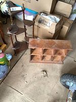 Photo showing both the small corner knick knack shelf and the six-compartment shelf on a concrete floor with other items nearby.